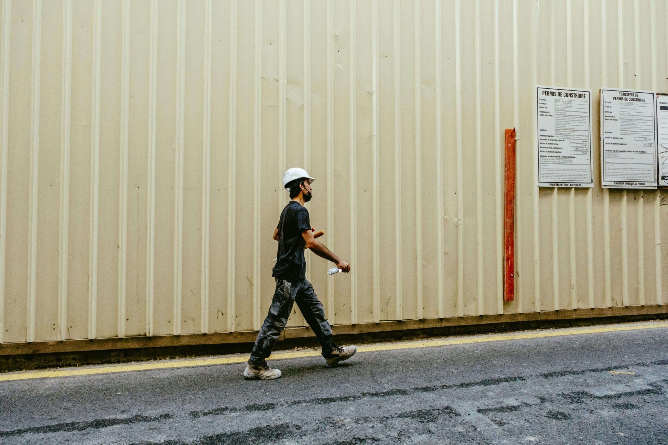 Construction worker in a hard hat walking beside a jobsite wall, representing a Nevada workers’ compensation claim and compromise and release settlement.