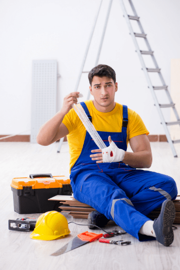 A worker in safety gear sits on the floor with tools. Worker's compensation may apply.