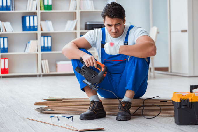 An injured worker in overalls sitting on the floor with a power tool. Need Worker's Compensation Lawyer help