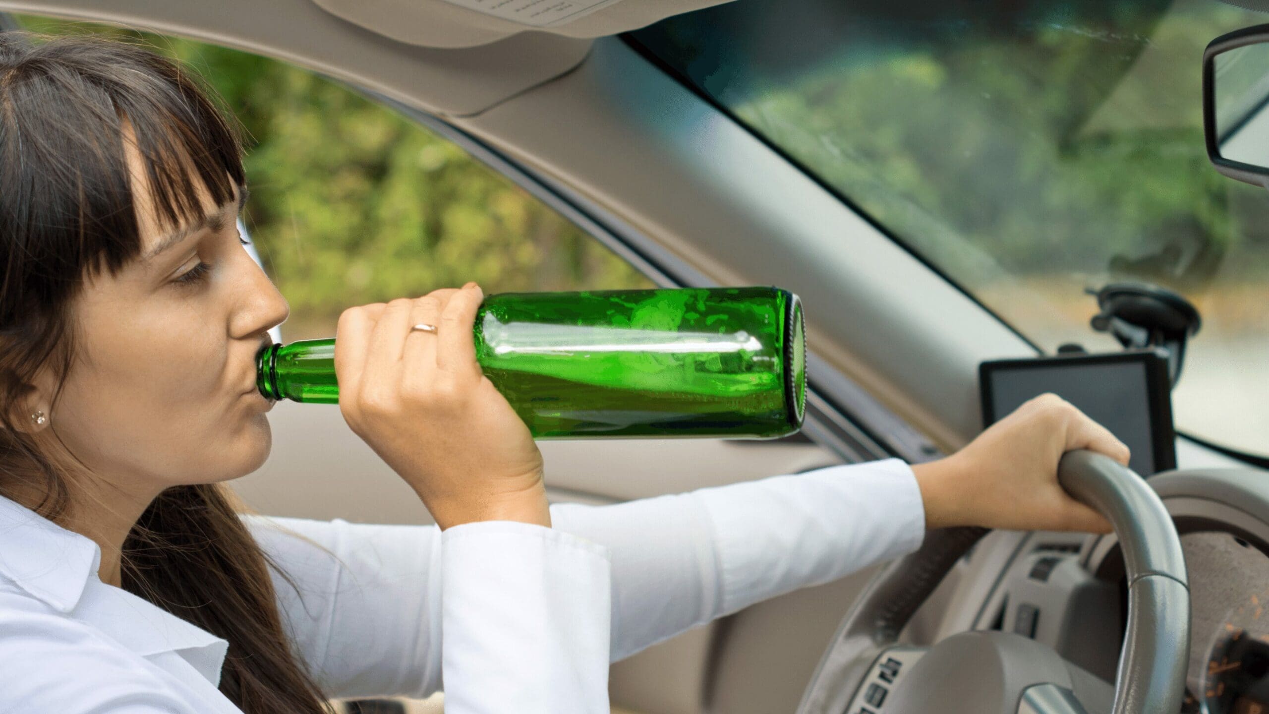 Woman seen drinking from a bottle while driving. Risky behavior depicted.