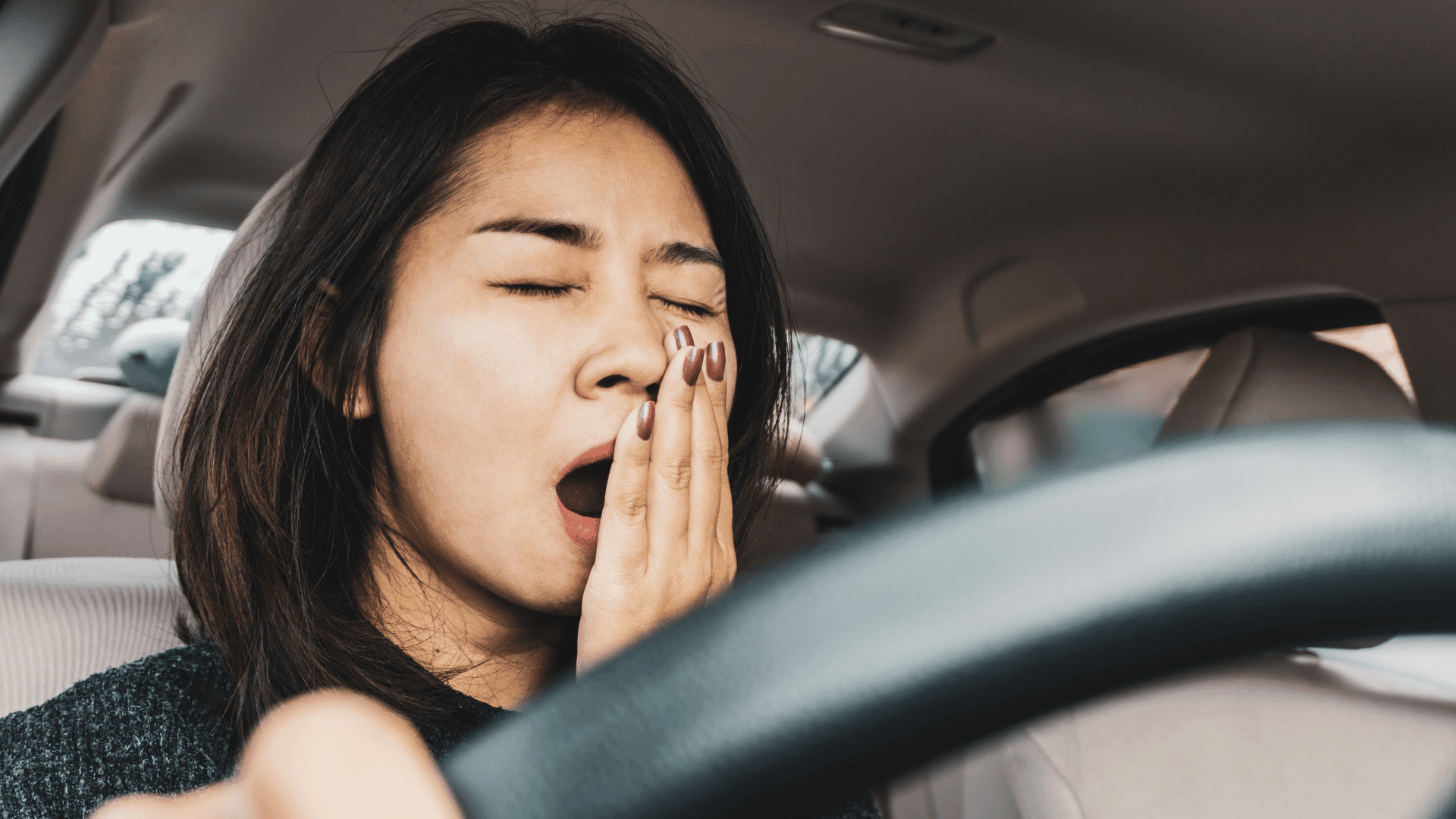 Image of a woman yawning while driving.