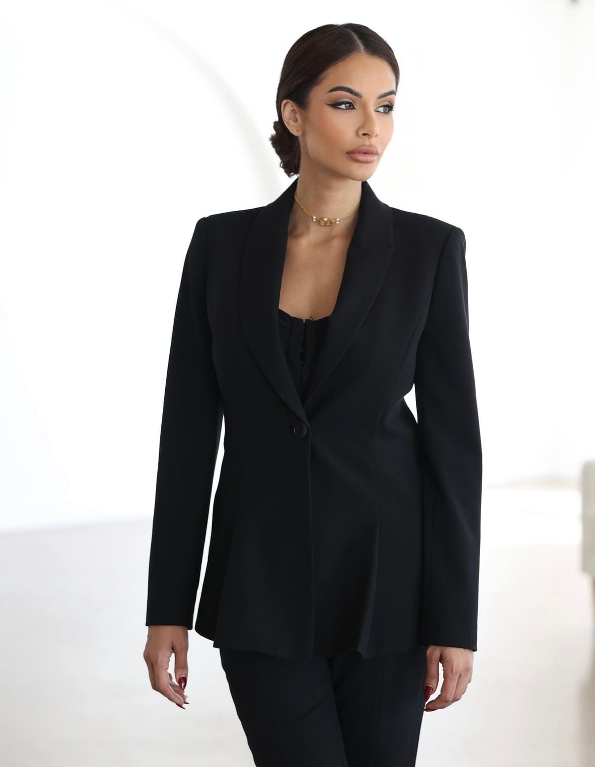 Meesha Moulton dressed in a tailored black blazer and pants, looking poised and authoritative against a clean white background.